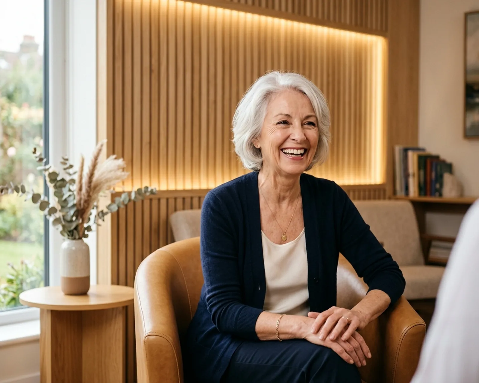 Woman in her 70s laughing warmly in a dental consultation room