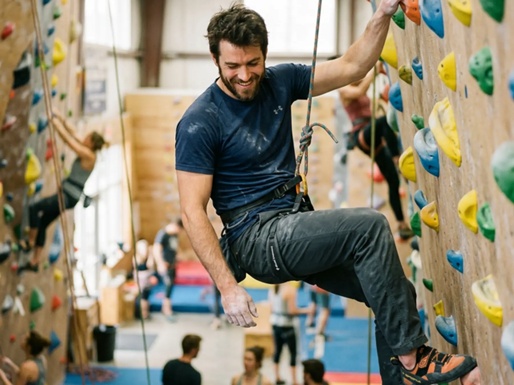 Man in a harness smiling on an indoor climbing wall