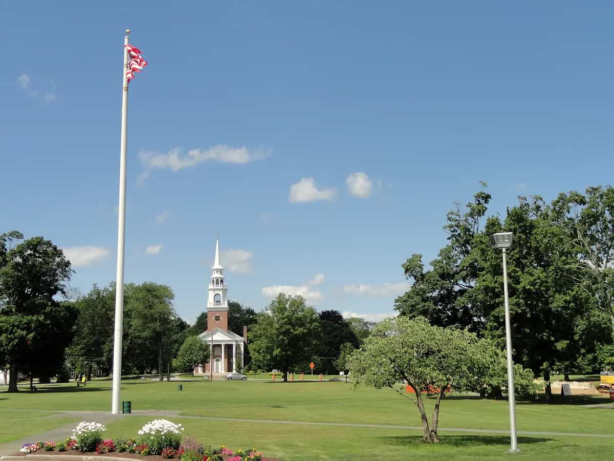 The white First Parish Church steeple rising over the tree-lined Framingham Centre Common in Framingham, Massachusetts