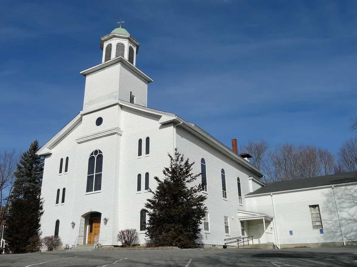 The white-clapboard First Church in Marlborough with its green-domed belfry against a clear blue sky in downtown Marlborough, Massachusetts