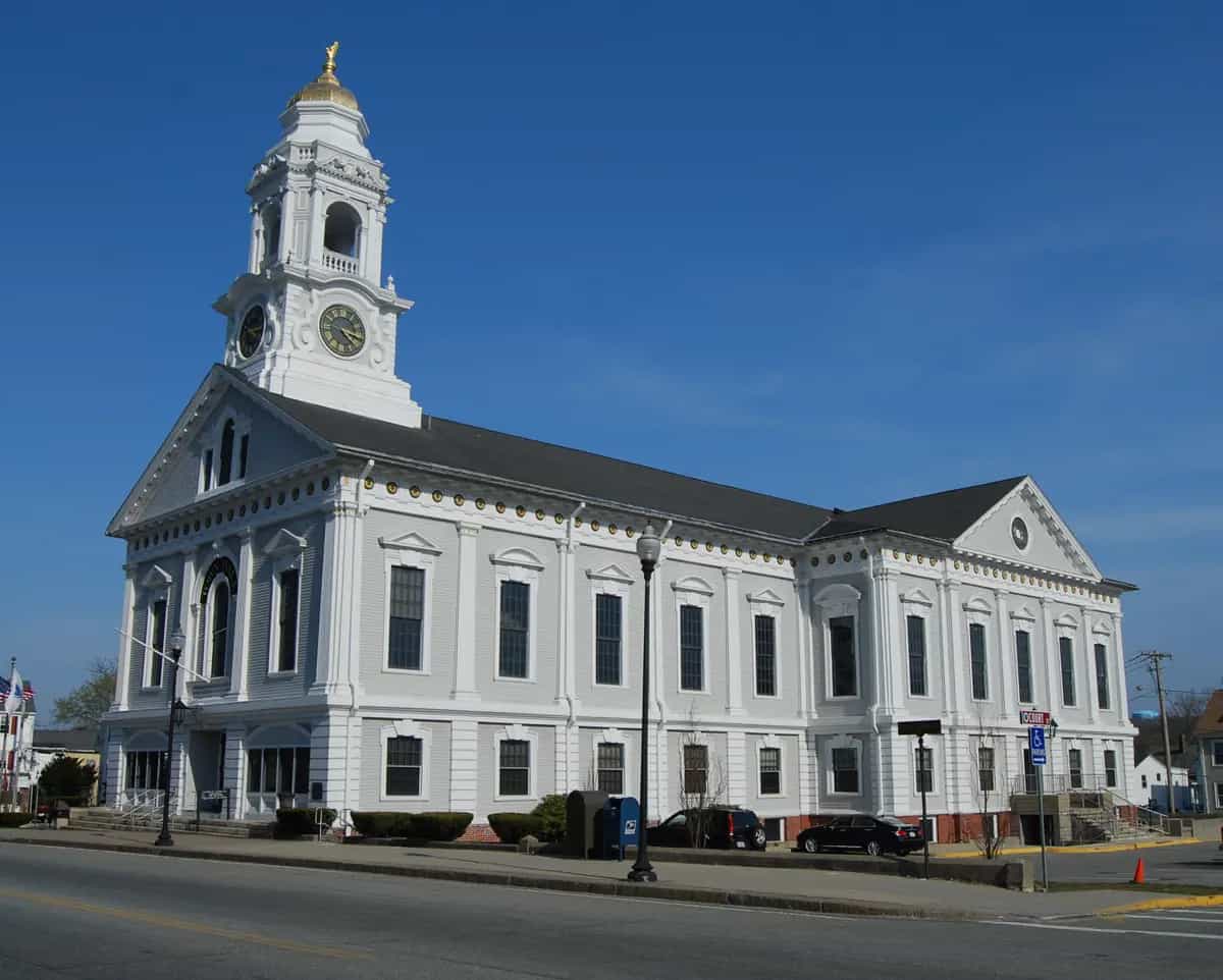 The white Italianate Milford Town Hall with its gold-domed clock tower under a clear blue sky in downtown Milford, Massachusetts