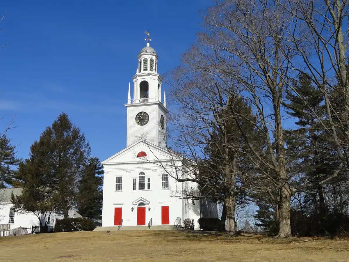 The white-steepled First Parish Church, a historic New England meetinghouse with a clock tower, against a clear blue sky in Northborough, Massachusetts
