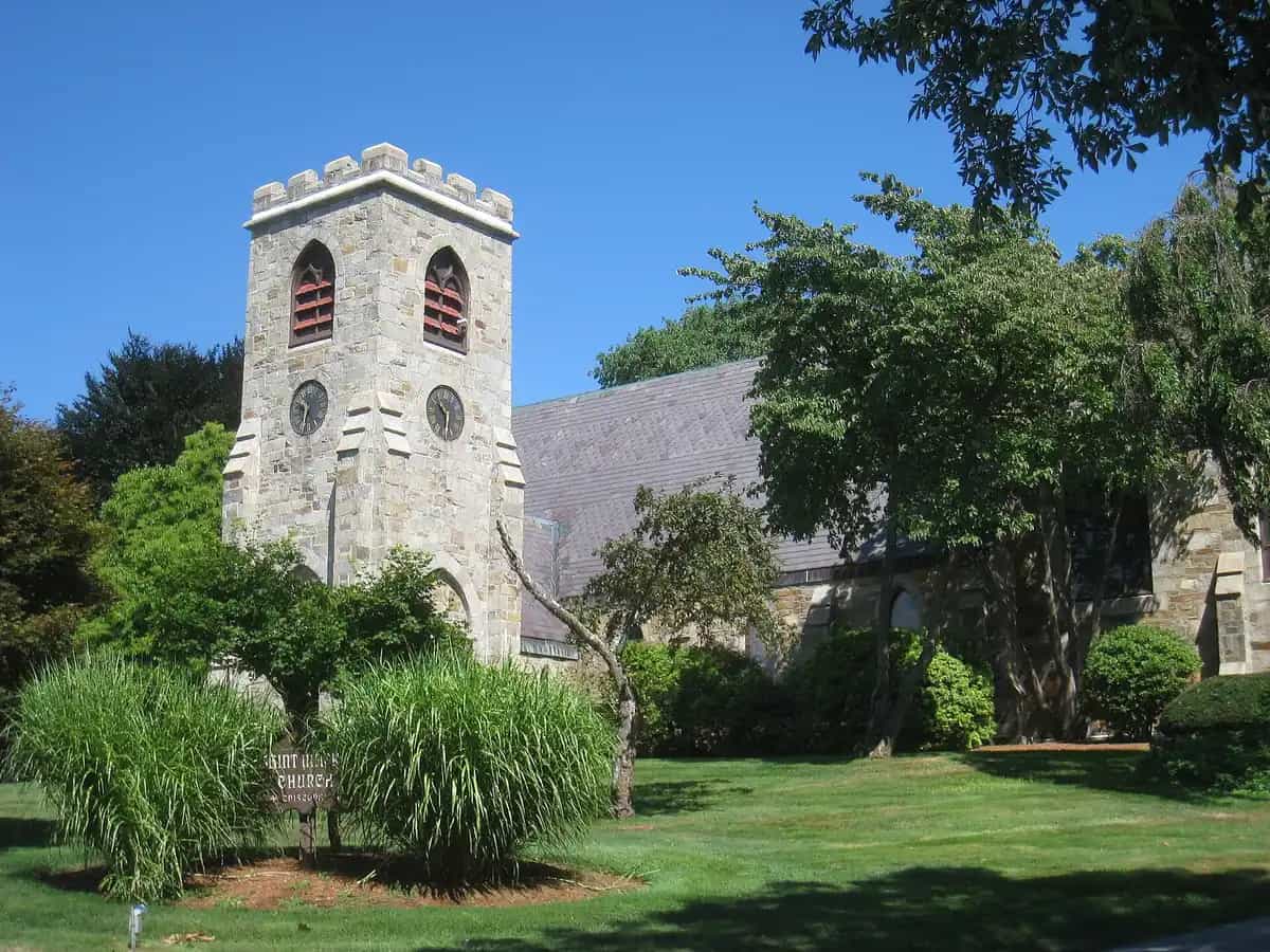 The stone Gothic Revival bell tower of St. Mark's Church on Main Street in the historic center of Southborough, Massachusetts, framed by mature shade trees