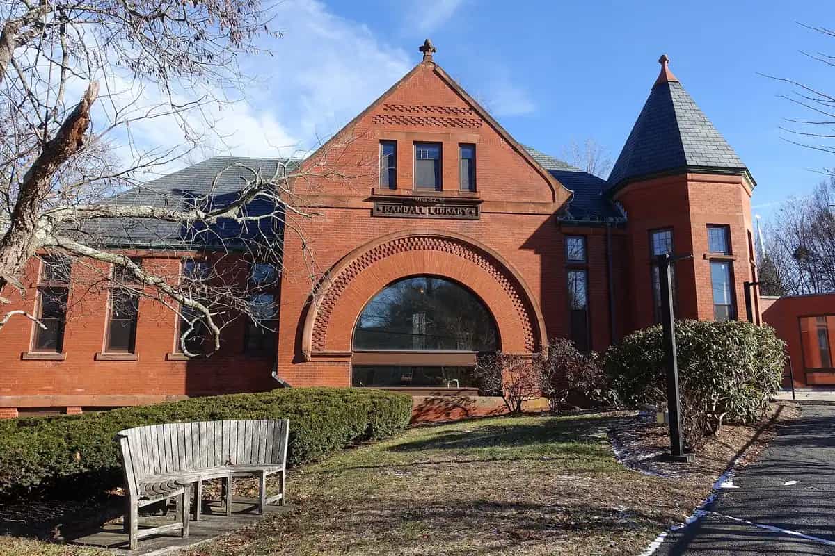 The historic red-brick Randall Library with its arched entrance and turret in Stow, Massachusetts, under a clear blue sky